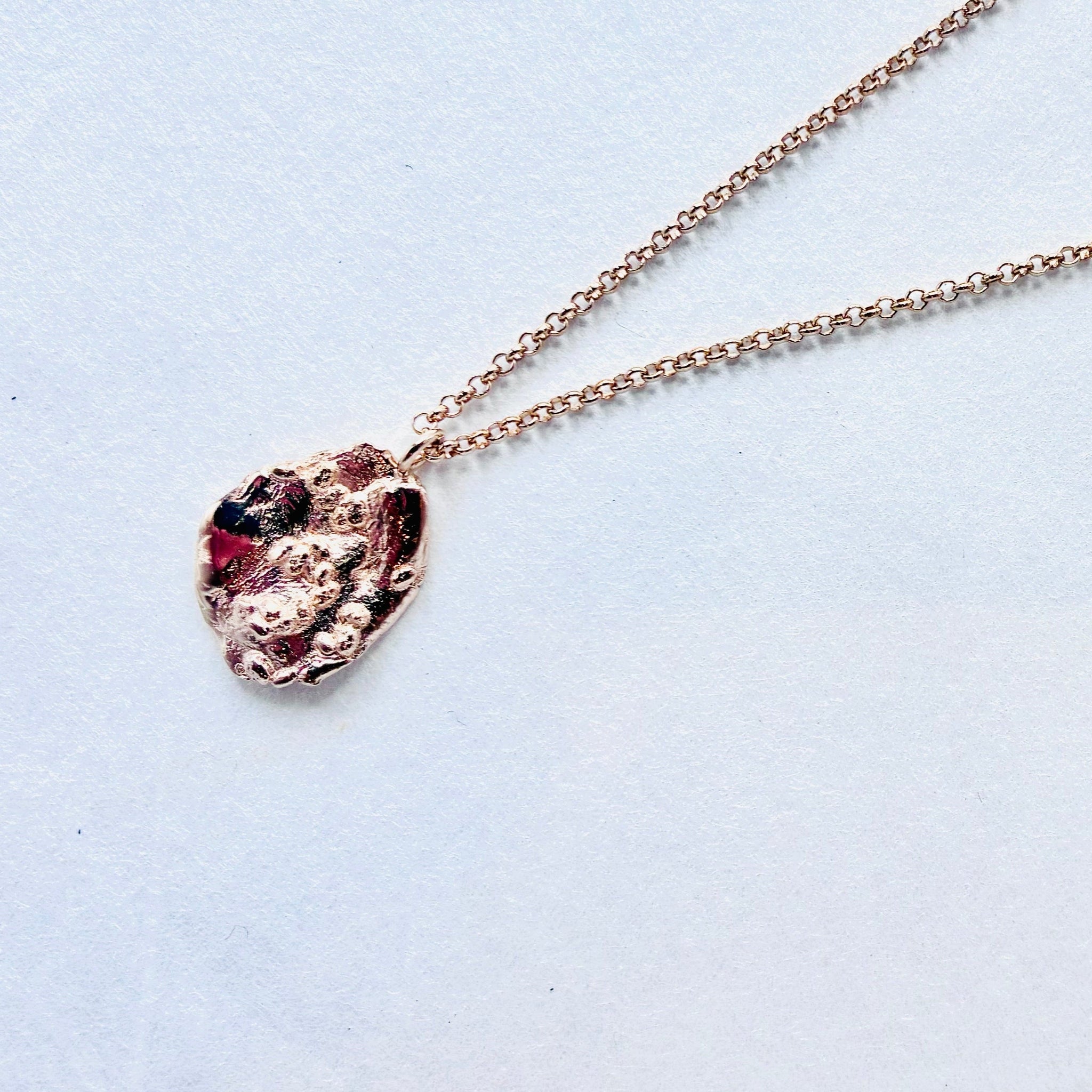  gold necklace with a unique pendant on a light blue background