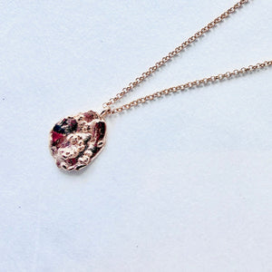  gold necklace with a unique pendant on a light blue background