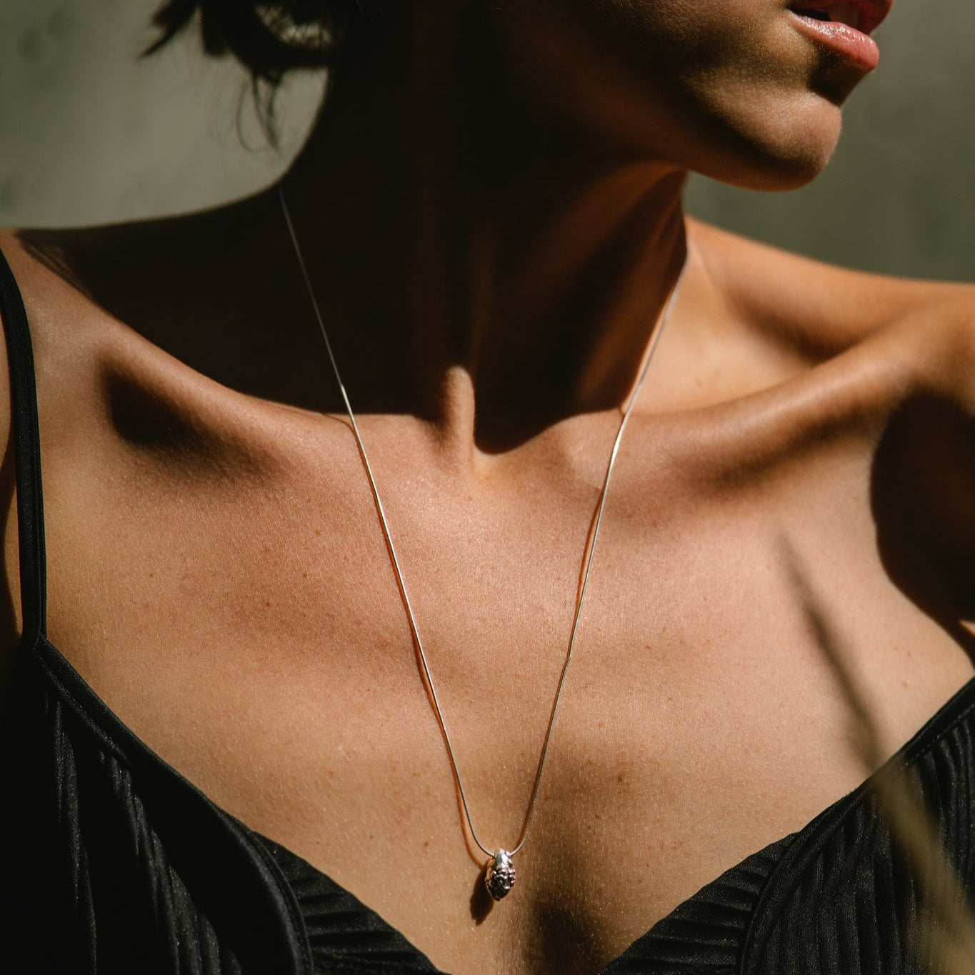 Close-up of a woman wearing a delicate silver necklace with a small pendant made by what if you stayed