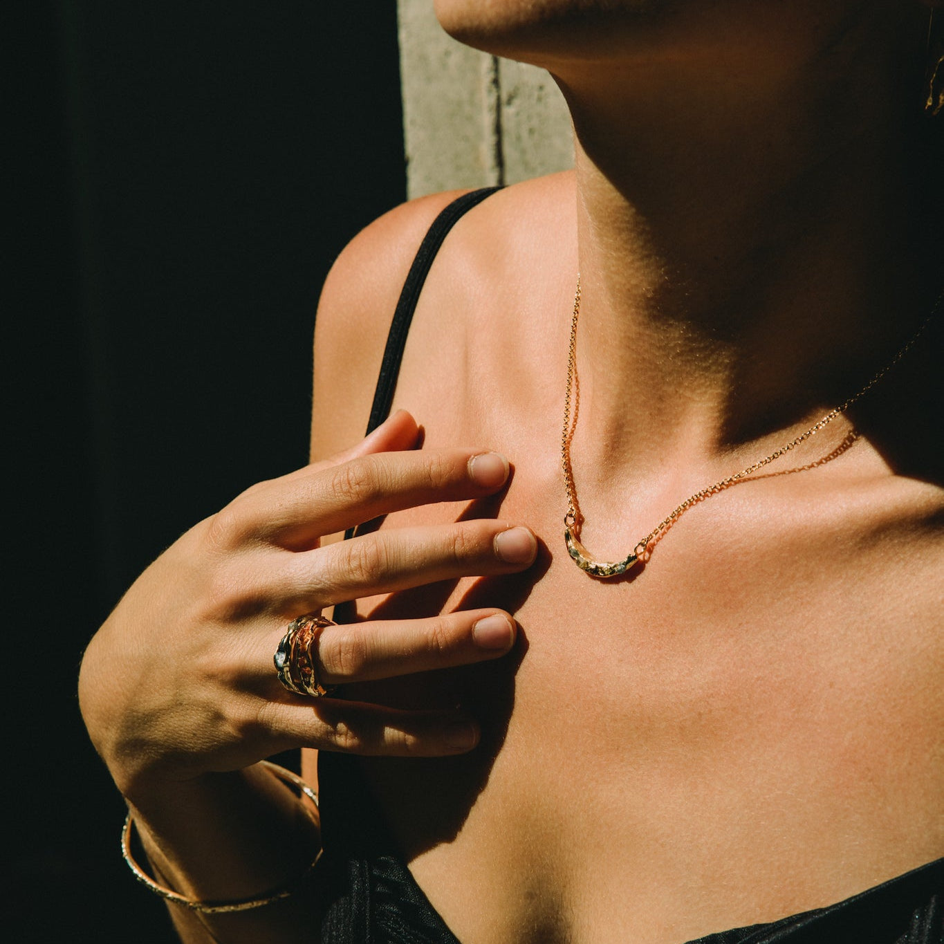Close-up of a young woman wearing a black top and gold jewelry made by What If You Stayed