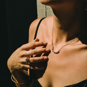 Close-up of a young woman wearing a black top and gold jewelry made by What If You Stayed