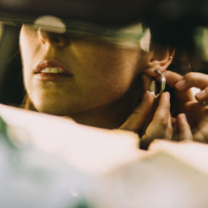 Young Woman with Dark Hair Wearing Silver Ribbon Earrings and Silver Necklace From What If You Stayed Jewelry  In Car