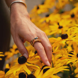 Hand with a ring touching yellow flowers