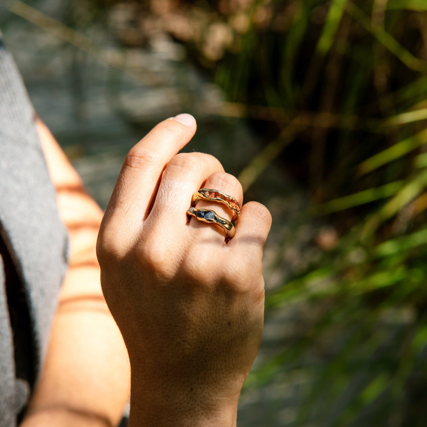 Hand with a ring holding onto a branch with a natural background