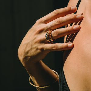 Hand with a gold ring on a dark background