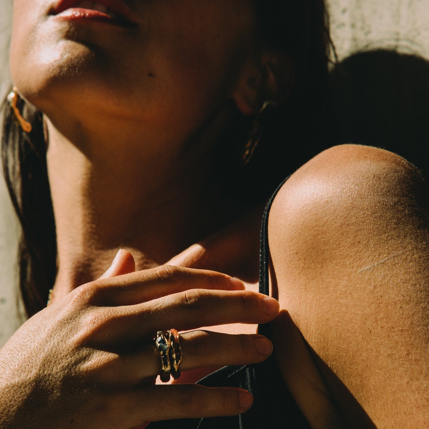 Close-up of a person's hand with a ring, wearing a black top against a blurred background