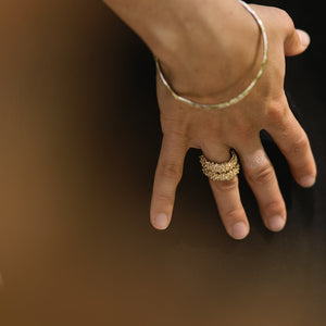 Hand wearing two gold rings on a dark background