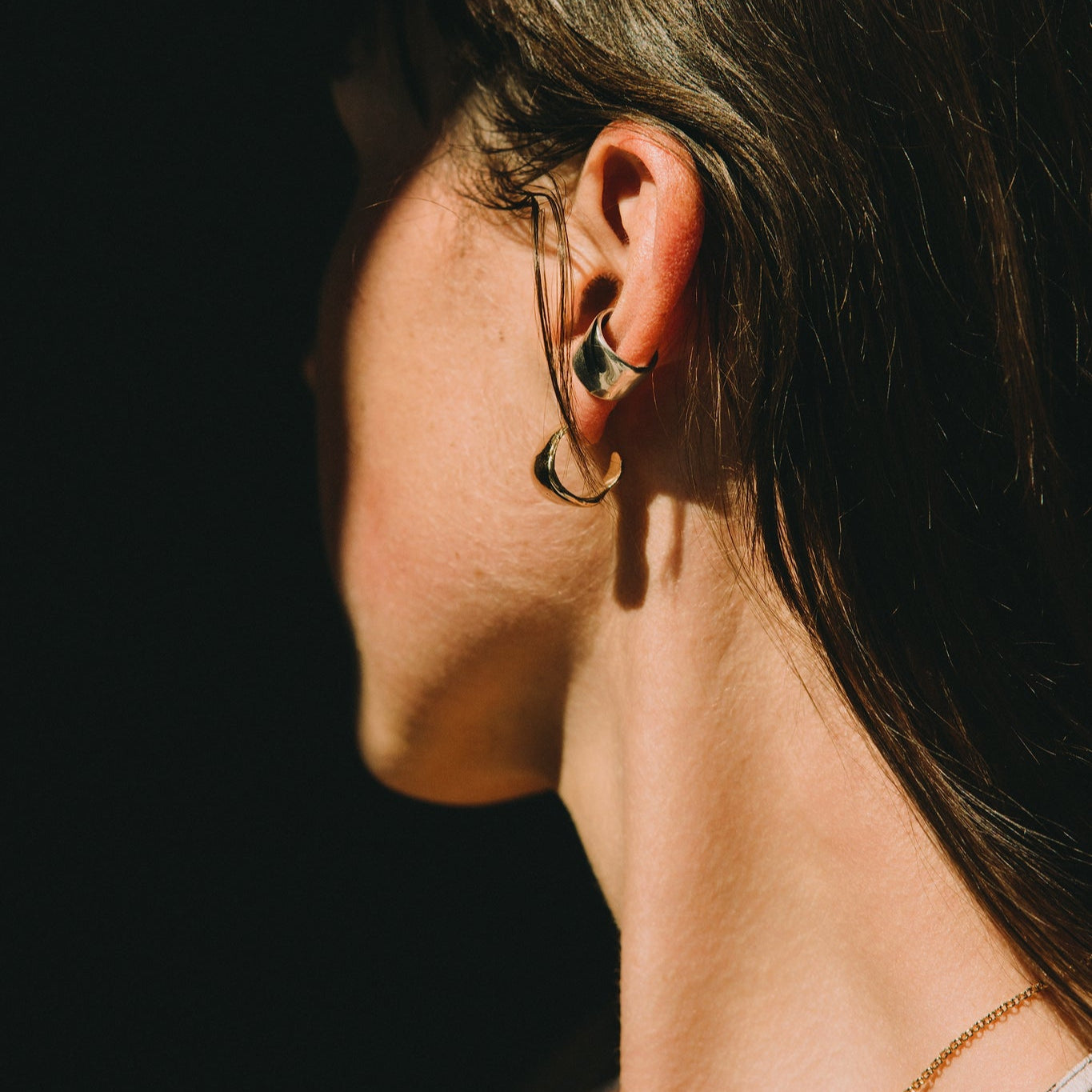 Woman wearing a leopard print top against a dark background with a gold necklace textured and small earrings hoops minimalist style made by what if you stayed jewelry