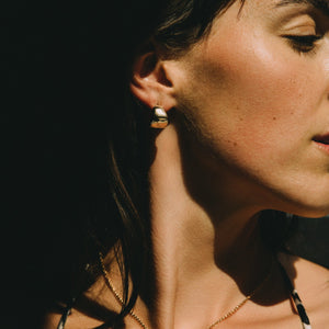 Woman wearing a leopard print top against a dark background with a gold necklace textured and small earrings hoops minimalist style made by what if you stayed jewelry