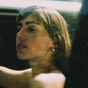 Woman with dark hair looking out of a car window wearing minimalist gold earrings hoops made by what if you stayed