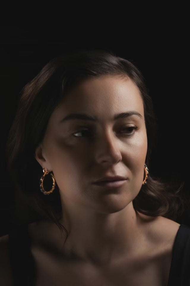 woman with brown long hair on black ackground wearing gold earrings hoops made by what if you stayed