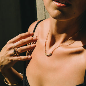 Young woman in sunlight outdoor wearing a black top with gold jewellery made by What If You Stayed
