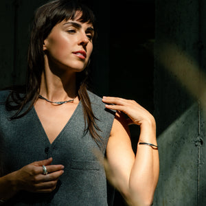 Woman wearing a dark gray sleeveless dress and silver jewellery made by what if you stayed against a dark background