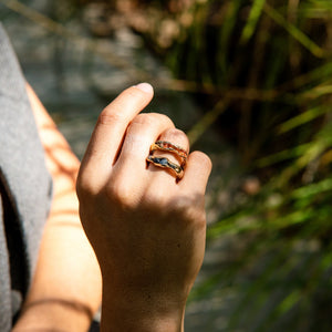 Close-up of a hand with a ring, blurred natural background